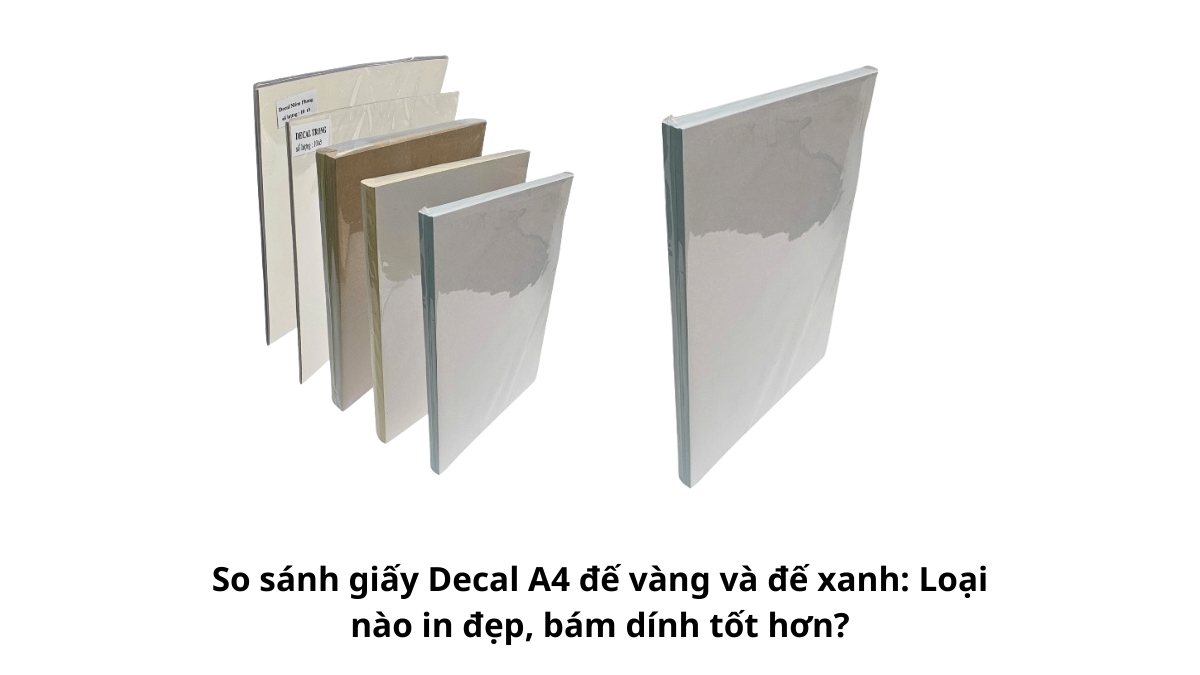 Hai xấp giấy decal A4 đế vàng và đế xanh đặt cạnh nhau trên bàn làm việc để so sánh sự khác biệt về màu sắc lớp đế và bề mặt giấy in.