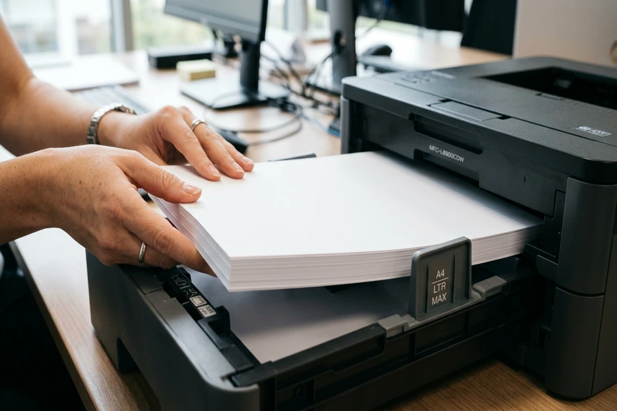 Thao tác nạp xấp giấy in A4 phẳng phiu vào khay máy in văn phòng