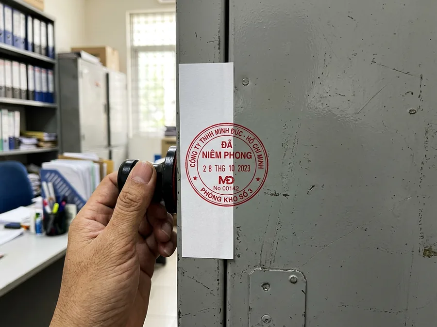 Dấu đỏ đóng giáp lai: một nửa trên dải giấy niêm phong, một nửa trên cánh tủ
