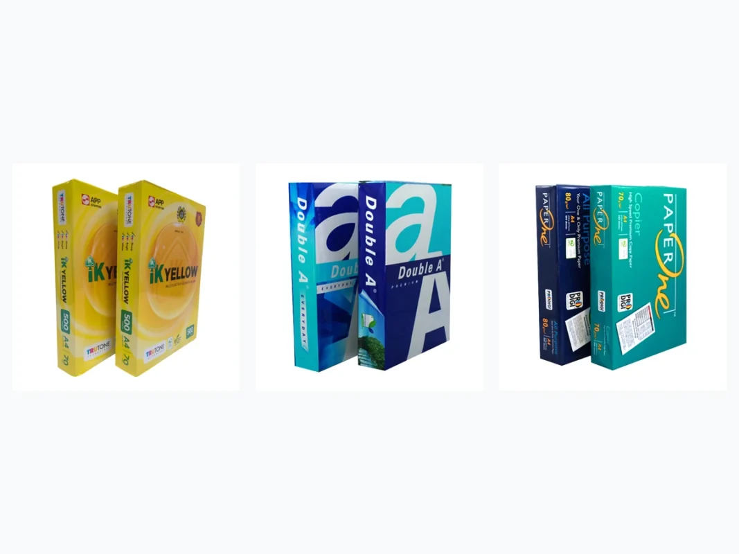 Ba ram giấy in văn phòng IK Yellow Double A và Paper One đặt cạnh nhau trên bàn làm việc
