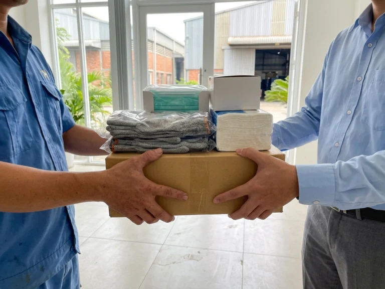 Nhân viên Phúc Thịnh trao thùng hàng gồm găng tay len, khẩu trang và khăn giấy lau tay cho nhân viên văn phòng nhà máy trong Khu chế xuất Tân Thuận, phường Tân Thuận